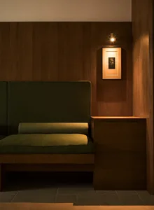 A green upholstered sofa with wooden cushions and walls.