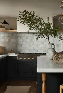 Contemporary residential kitchen with white, gray, and black tile backsplash, black cabinetry, and a marble countertop.