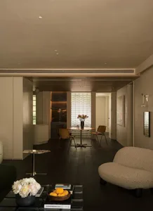 A modern, neutral-toned living room with a round table, chairs, and a sofa.