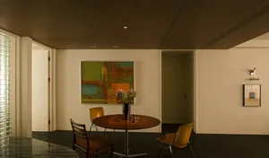 A modern residential interior featuring wood, glass, and metal furnishings