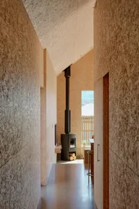 An interior hallway featuring minimalist design elements, including a high ceiling, textured walls, and a floor-to-ceiling wi