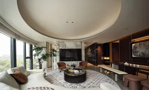 Modern living room with a large white sofa, round black coffee table, large windows, and marble accents.