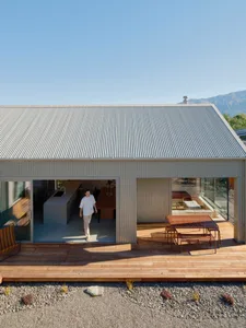 A contemporary house with corrugated metal siding and a wooden deck.