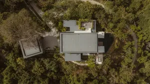 A modern residential home with concrete exterior surrounded by greenery.