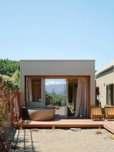 An industrial-style bathroom with a metal bathtub, glass doors, and corrugated metal walls.