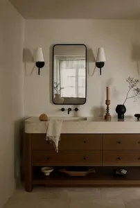 A modern minimalist bathroom with a stone countertop and wooden drawers.