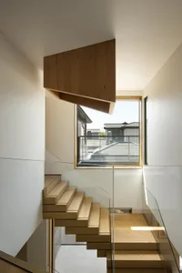 Modern indoor staircase with wooden steps and transparent glass railing.