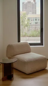 Modern living room featuring a textured gray fabric armchair and a small round glass-top side table.