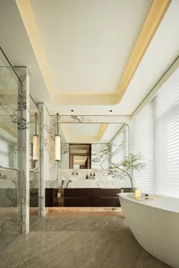 Modern bathroom with marble walls and ceiling, a freestanding bathtub, and a shower area.