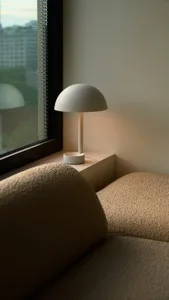 A modern minimalist interior with a sleek, white table lamp emitting warm, ambient light.