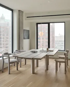 A modern residential dining room featuring wooden furniture and concrete columns.