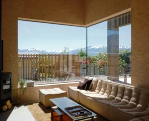 Modern minimalist living room with large glass window overlooking mountains, featuring a comfortable sofa with cushions, a lo