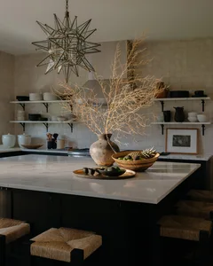 A modern kitchen with concrete cabinets, marble countertop, and decorative dried plants.