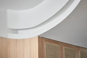 A close-up image of a modern interior design showing a plaster ceiling with curved lighting fixtures.