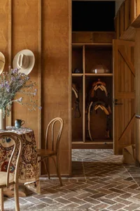A rustic storage room with wooden furniture and horse equipment hanging on the wall.