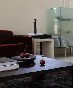 Modern living room with wooden coffee table, red cherries, dark furniture, and glass cabinet.