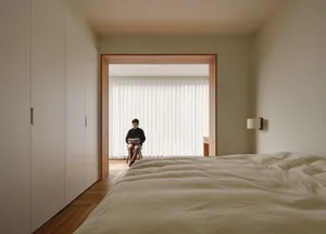 A minimalist bedroom with white textured fabric and wooden floor.