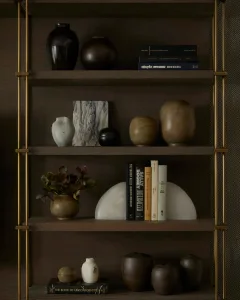 A modern interior bookshelf featuring ceramic vases and books, including titles like 'Utopia Avenue', 'The Shadow Killer', an