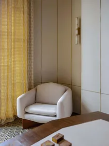 Modern luxury interior with a comfortable white armchair and elegant yellow curtains