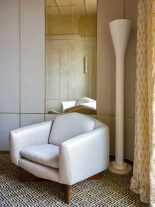 Modern living room featuring a white upholstered armchair with a textured fabric design, complemented by a floor lamp and a p