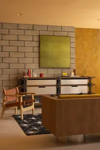 A modern living room featuring concrete walls, wooden furniture, and fabric seating.