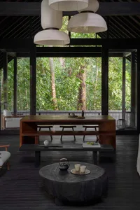 A minimalist living room with wooden furniture and a large window overlooking greenery.