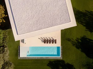 A drone view of a modern concrete architectural landscape with a swimming pool and garden.