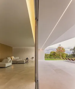 A modern minimalist living room featuring floor-to-ceiling windows, concrete flooring, and wooden walls.