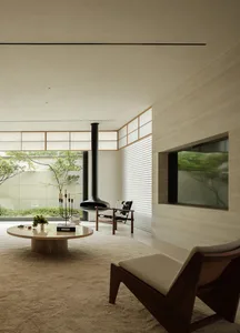 Contemporary living room with minimalist design, featuring wooden paneling, glass coffee table, and concrete flooring.