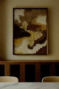 A piece of abstract art made from paper-cutting techniques, featuring layers of brown, white, and yellow shapes.