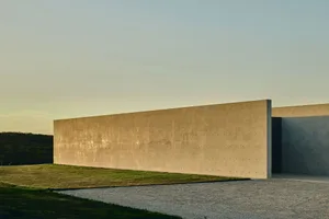A modern building exterior with a long, smooth concrete wall.
