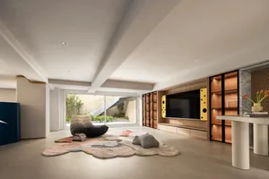 A modern living room featuring a cozy black lounge chair, a colorful rug, and a wooden bookshelf.