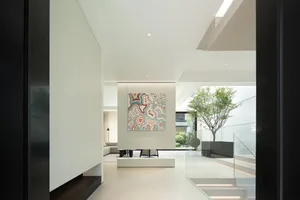 Modern minimalist white living room with glass walls and a colorful abstract painting on the wall.