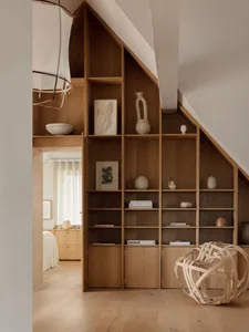 A modern minimalist bookshelf made of wood with various decor items and books displayed.