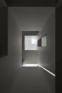 An minimalist white concrete corridor with a skylight letting in natural light.