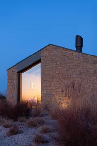 A modern house with a stone exterior during twilight.