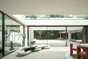 Modern living room with glass walls and concrete floor and furniture.