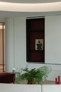 Contemporary living room with minimalist design, featuring wooden shelves, a leather sofa, and glass accents.
