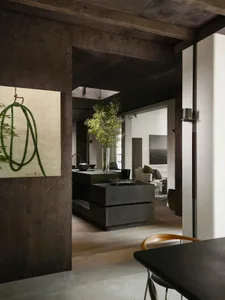 A modern industrial residential interior featuring a concrete kitchen island and wooden dining table with a dark wood floor.