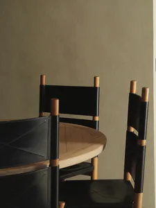 A modern interior design featuring wooden chairs with black leather seating and backrests.