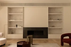 Modern living room with a black fireplace, concrete shelves, and wooden floor.