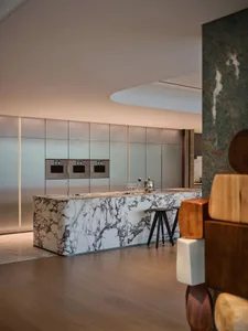 Modern minimalist kitchen featuring marble countertop and stainless steel appliances.