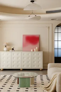 Minimalist living room with neutral-colored furniture and decor, featuring a round coffee table and a large abstract painting