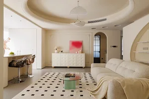Modern living room featuring a comfortable beige sofa, a round glass coffee table, and a bold pink artwork on a textured wall