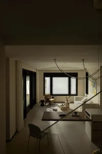 A modern-themed living room with a concrete floor, featuring minimalist furniture and large windows.