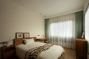 Modern minimalist bedroom with wooden furniture and glass windows.