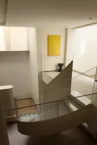 A modern minimalist staircase with transparent glass railings and steps, featuring minimalist design elements and a bright ye