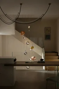 A modern staircase with hanging light fixtures featuring a mix of glass, marble, and metal materials.