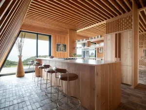 Modern kitchen with wooden island, stools, and open shelving.