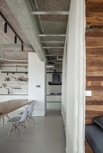 Industrial-style kitchen with concrete walls, exposed pipes, and minimalist furniture